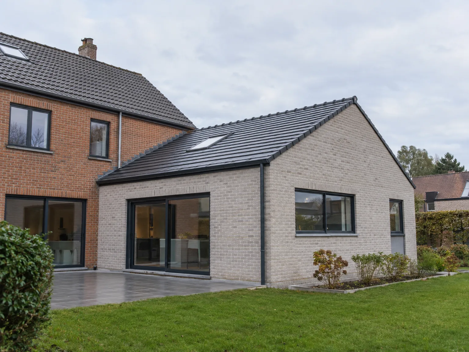 Extension de maison moderne avec nouvelle toiture ardoise et grandes ouvertures vitrées