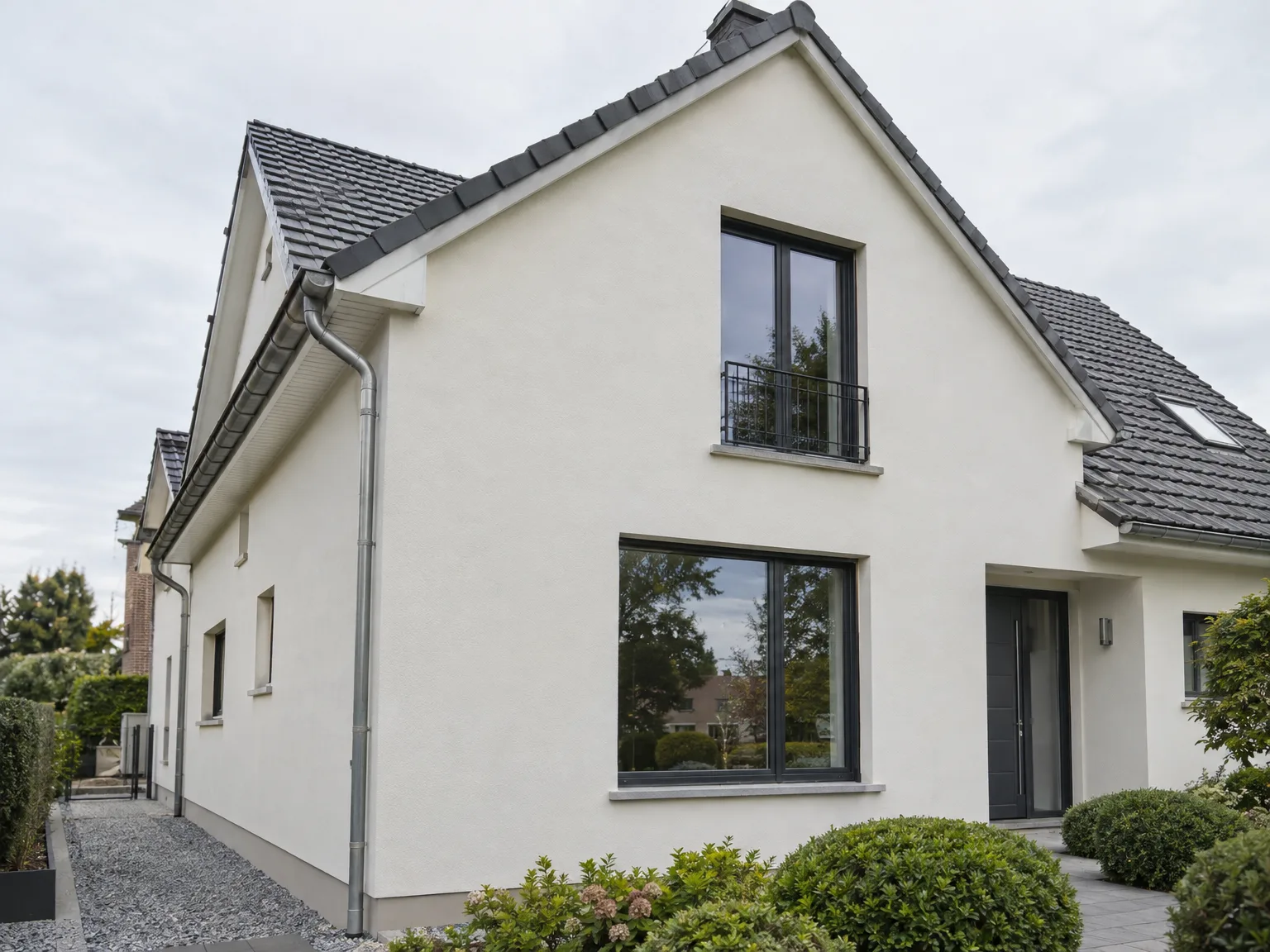 Rénovation de maison : façade blanche, toiture grise, gouttières et fenêtre de toit